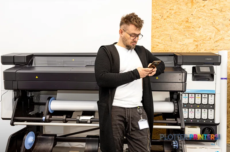 HP Latex 630 W Print and Cut Plus Solution lifestyle image showing a man operating the black printer in a studio setting