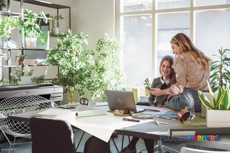HP DesignJet T850 36-in Printer lifestyle image showing two professionals reviewing printed designs in a bright office works…