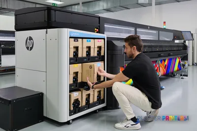 Technician accessing ink cartridges on HP Latex FS60 Printer in production facility lifestyle setting