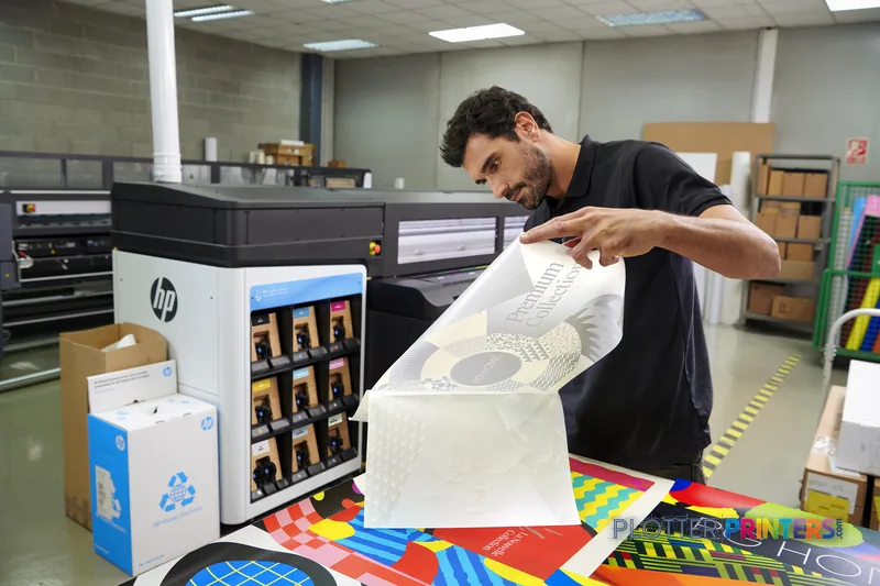 Man examining printed output from HP Latex 2700 W Printer in a print shop environment