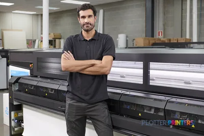 Man posing in front of HP Latex 2700 Printer in a print shop workspace