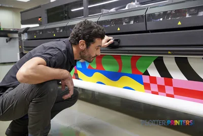 Operator inspecting vibrant color output from HP Latex 2700 Printer in production environment