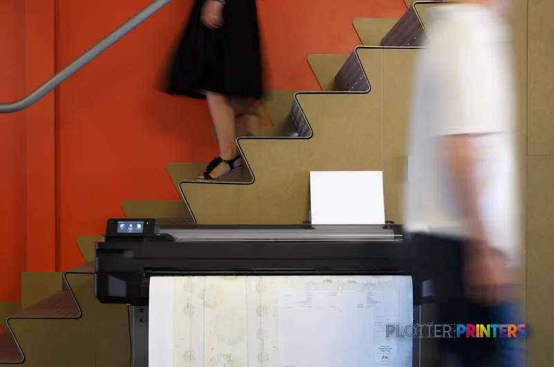 HP Designjet T520 large-format printer lifestyle image showing the device in an office setting with printed architectural pl…