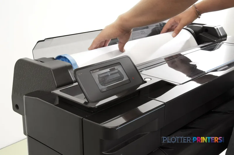 HP Designjet T520 lifestyle image showing a person removing a large-format color print from the printer's output tray