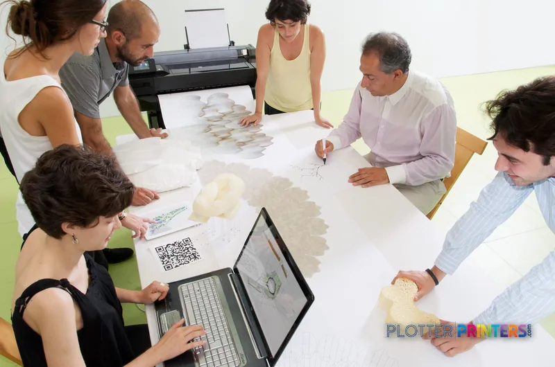 HP Designjet T520 large-format printer in lifestyle setting with team reviewing printed architectural drawings at table