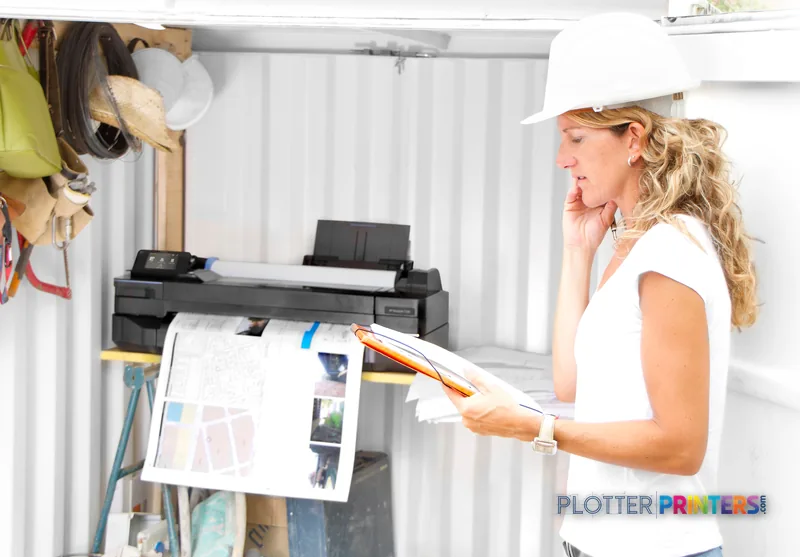 Woman in white shirt reviewing large-format print from HP Designjet T120 ePrinter in workshop setting