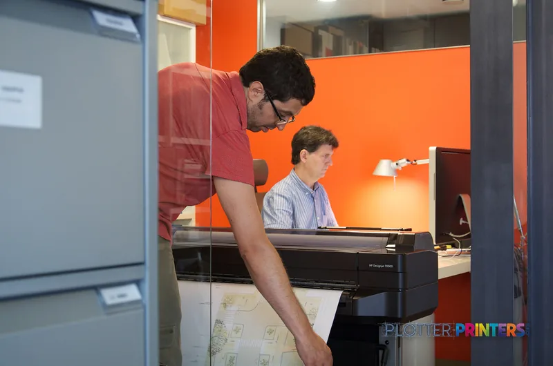HP Designjet T120 ePrinter lifestyle image showing two people in an office using the large-format printer