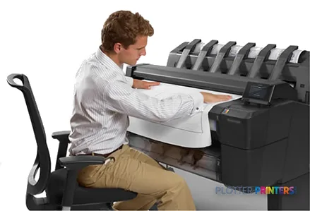 Man operating HP Designjet T2500 36-in eMFP large format printer, feeding paper into the device