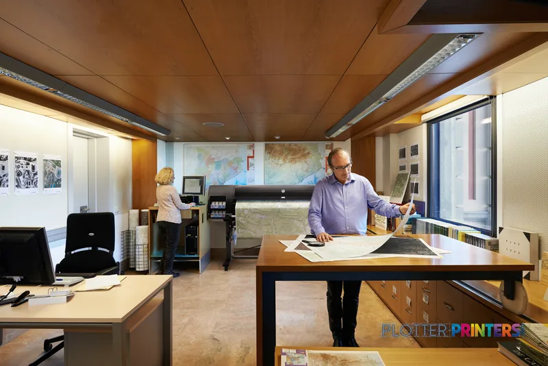 HP Designjet Z6800 lifestyle image showing the black printer in a professional office with a man reviewing large format prin…
