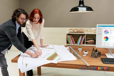 HP PageWide XL 5000 lifestyle image showing two professionals reviewing large-format color prints at a desk