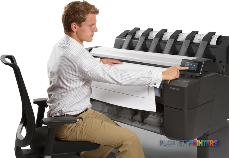 Man in office chair retrieving a large printed document from an HP Designjet T2530 printer