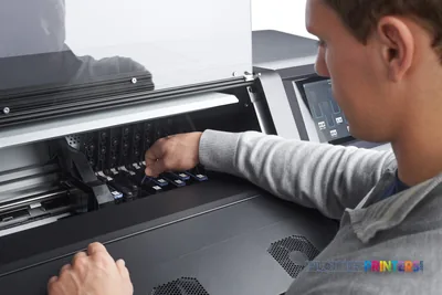 HP Latex 365 Printer lifestyle image showing a person installing ink cartridges into the grey printer