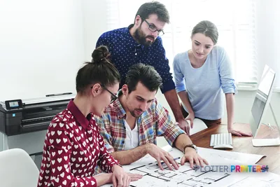 HP DesignJet T830 MFP lifestyle image showing team reviewing large format prints at desk