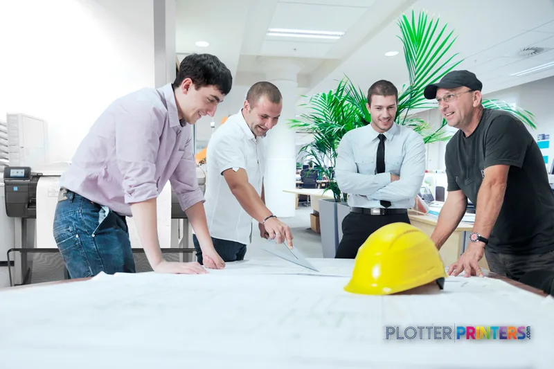 HP DesignJet T830 MFP lifestyle image showing team reviewing large format prints in office
