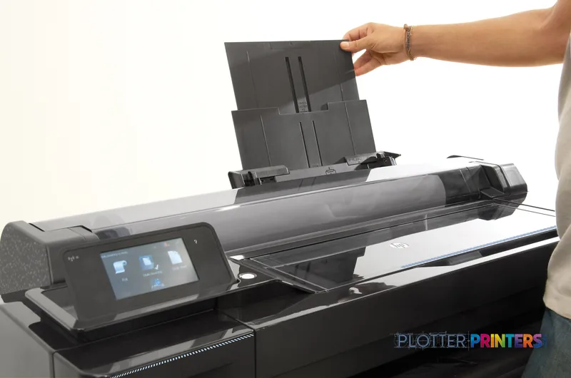 HP DesignJet T120 24" ePrinter lifestyle image showing a person loading paper into the black printer's input tray