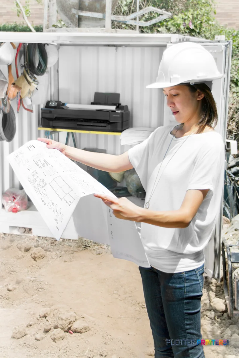 HP DesignJet T120 24" printer in a job site office with a worker reviewing large-format blueprints