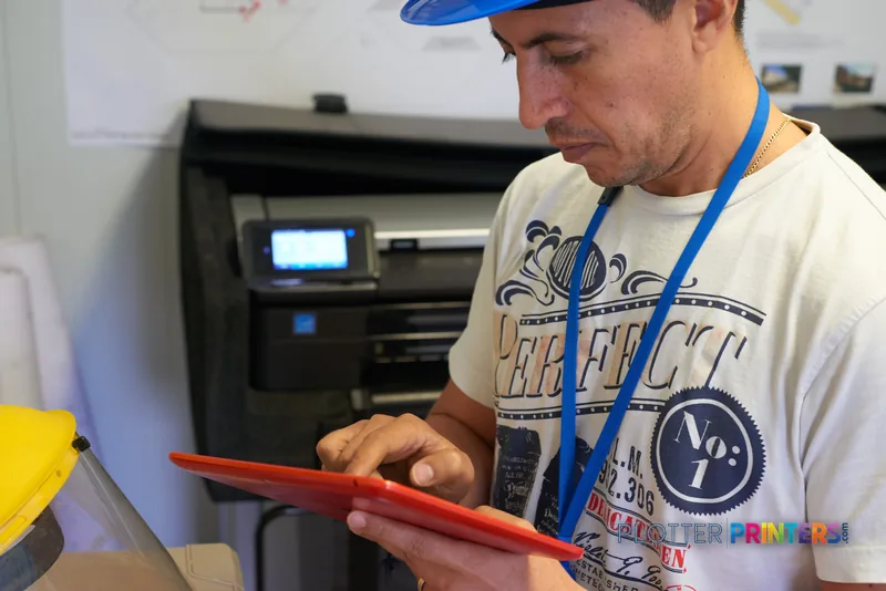 Man examining printed output from HP DesignJet T830 24" printer in office setting