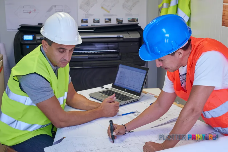 HP DesignJet T830 lifestyle image showing two construction workers reviewing blueprints with the printer in background