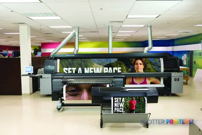 HP Q6675C large format printer lifestyle image showing the device printing colorful banners and signage in a bright studio e…