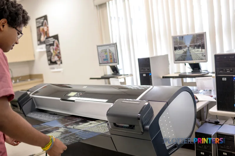 HP Designjet Z5200 large format printer lifestyle image showing person feeding media into the device in an office setting