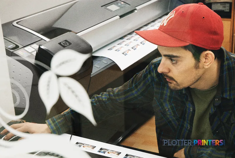 Man in red cap examining large format print output from HP Designjet Z5200 printer in studio setting