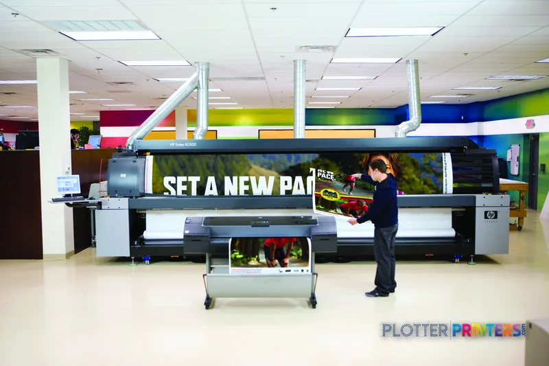HP Designjet Z2100 24-in Photo Printer lifestyle image showing the printer in a bright showroom with a person viewing colorf…