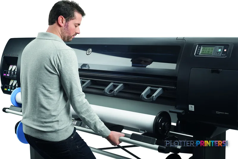 Man operating the HP DesignJet Z6610 60-in Production Printer in a lifestyle setting, loading media into the black printer