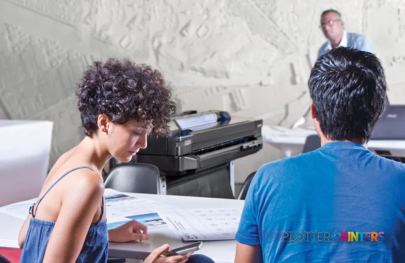 HP DesignJet T525 36-in Printer product detail image showing the white large-format printer in an office setting with users
