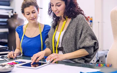 Two professionals reviewing color swatches at a workstation with an Epson SureColor SC-F9400H printer in the background