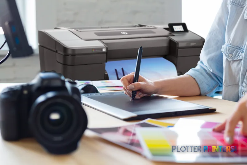 HP DesignJet Z9+ 24-in PostScript Printer lifestyle image showing designer working at desk with tablet pen
