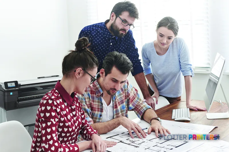 HP DesignJet T830 24-in Multifunction Printer lifestyle image showing team reviewing large-format prints at desk