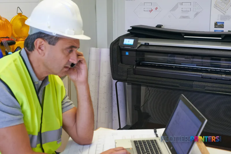 HP DesignJet T830 36-in Multifunction Printer in a construction office setting with a worker in safety gear